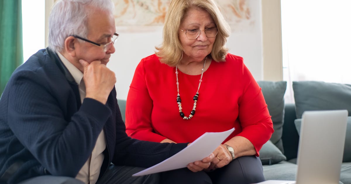 Elderly couple reviewing financial documents together at home in Portugal