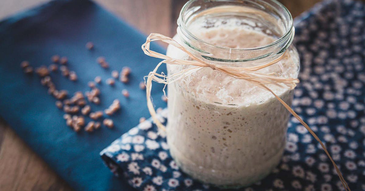 Rustic homemade yogurt in a glass jar tied with twine on blue floral cloth for breakfast