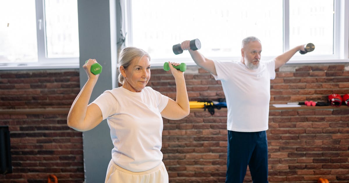 Elderly man and woman workout with dumbbells promoting healthy lifestyle and fitness