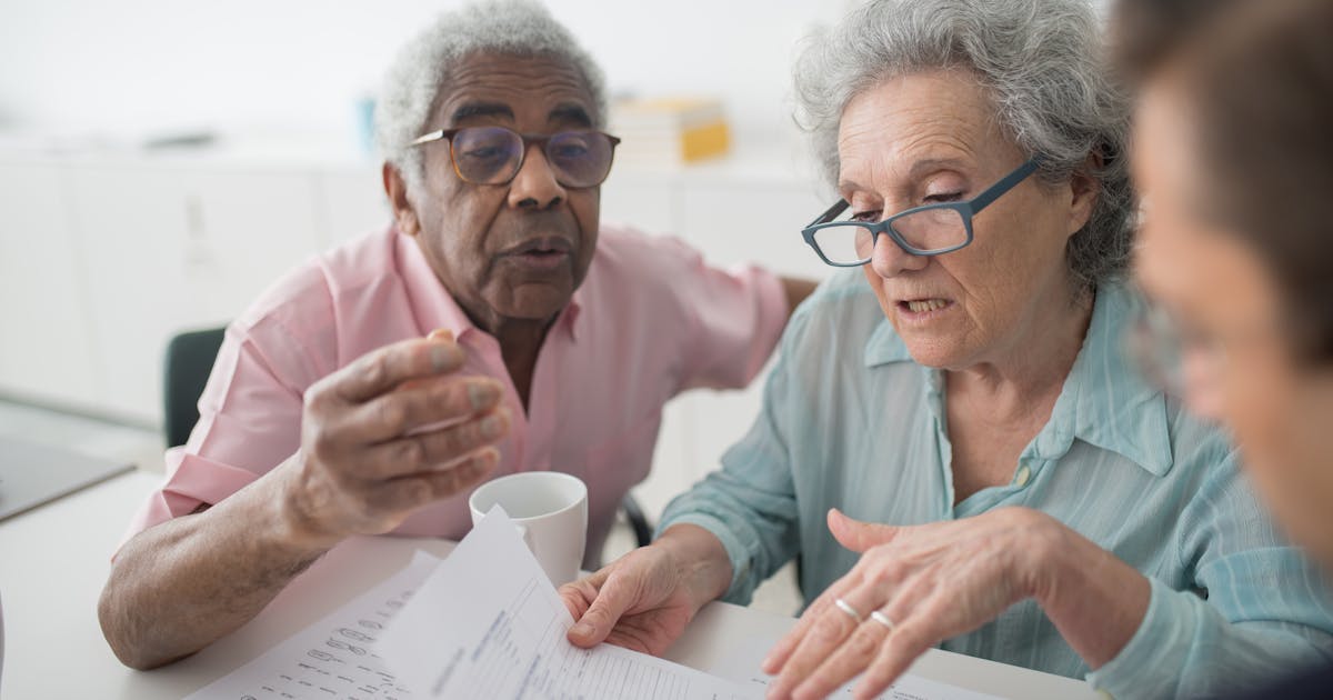 Elderly couple discussing financial documents with a consultant in an office setting