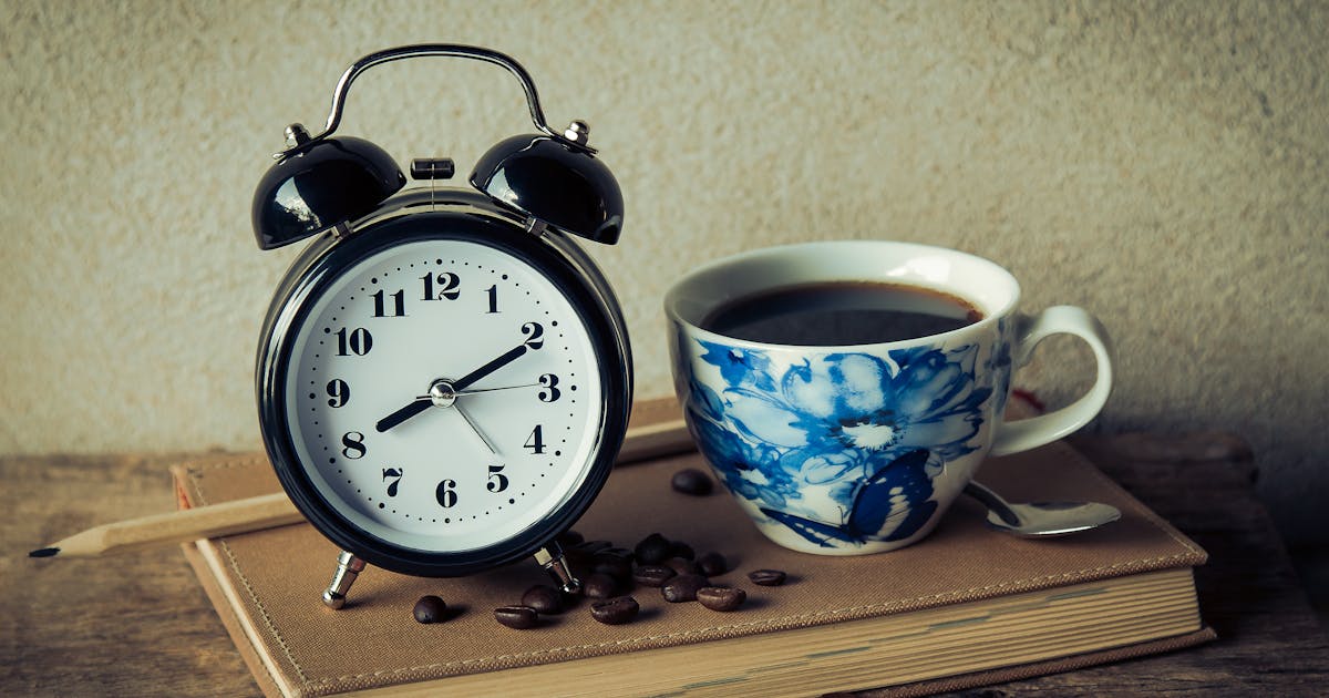 Vintage alarm clock and floral coffee cup on a book