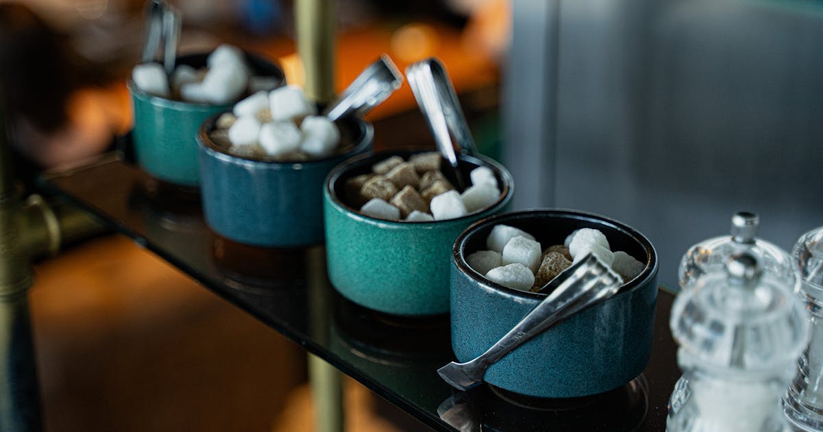 Colorful sugar bowls with tongs in a cozy cafe setting
