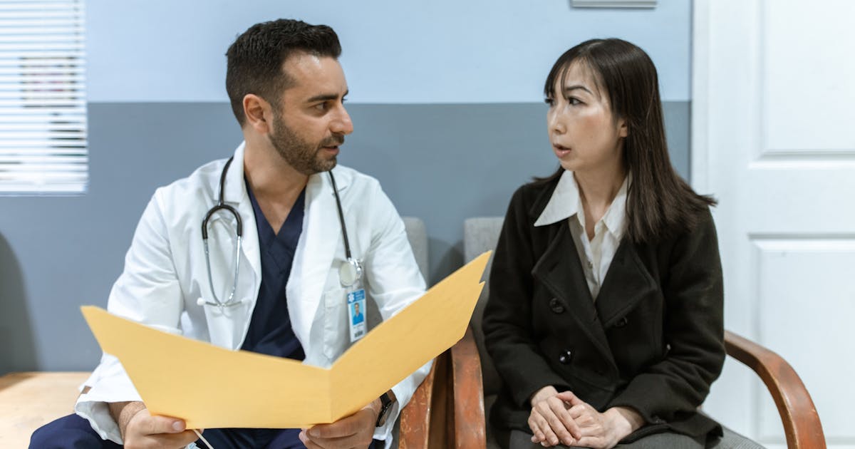 Healthcare professional consulting with a patient in a clinical setting discussing treatment