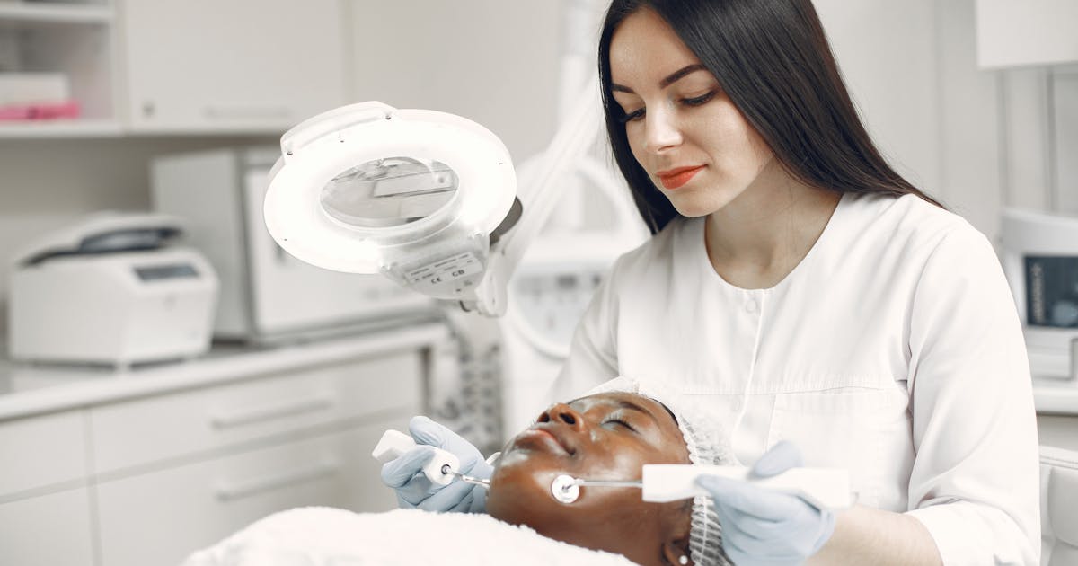 A dermatologist applying a skincare treatment to a relaxed client in a modern clinic
