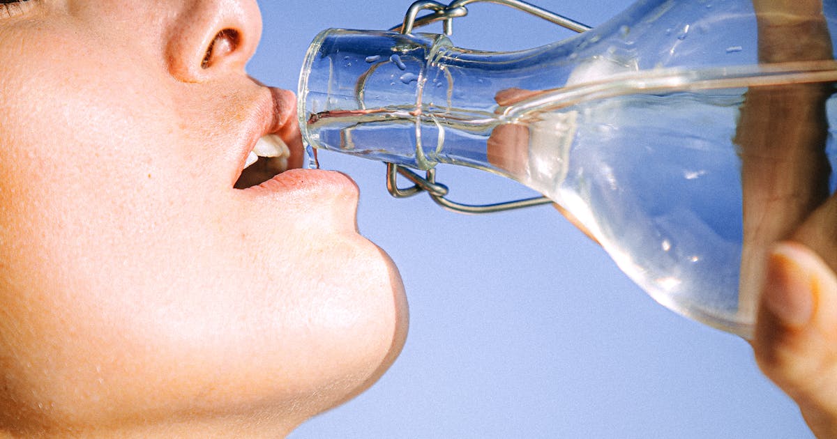 Woman drinking water from a glass bottle