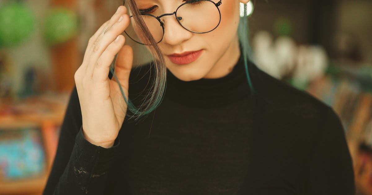 A woman wearing eyeglasses while reading a book