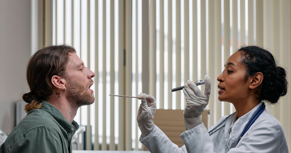 A doctor examining a patient's throat during a clinical visit