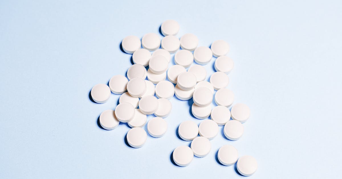 White round vitamin pills on a sky blue surface