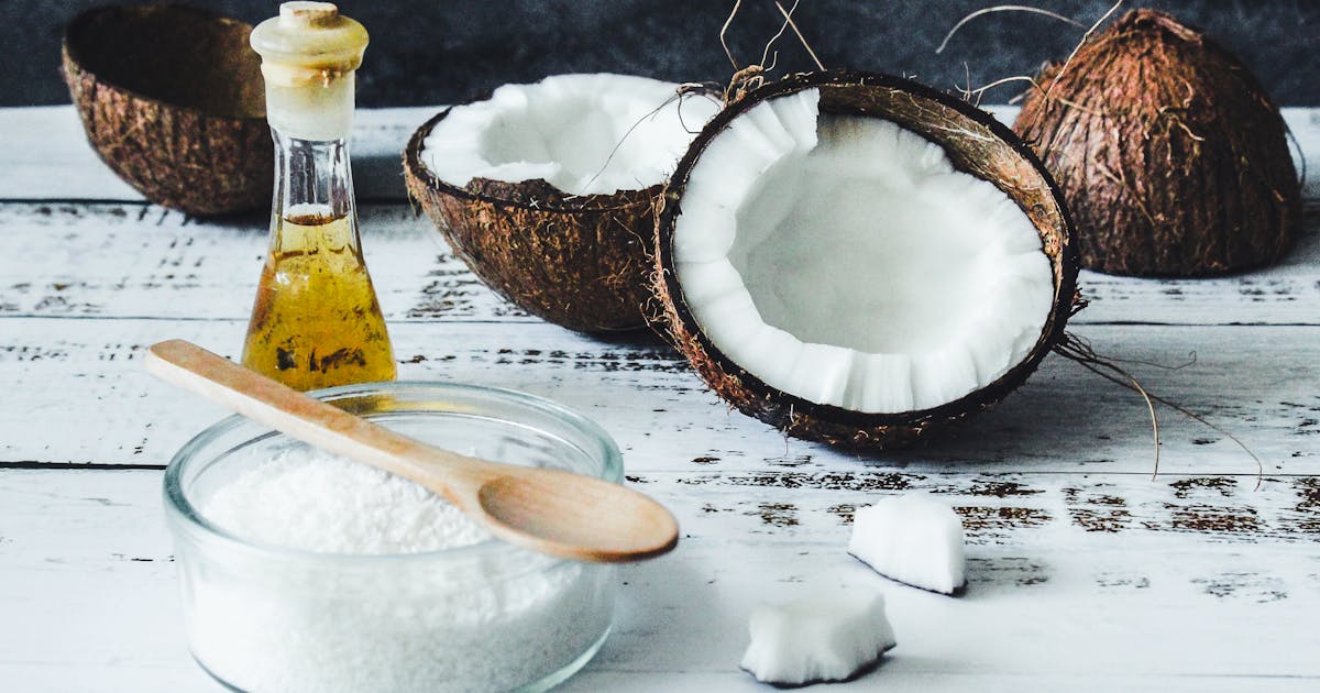 White protein powder in clear glass jar beside wooden spoon on minimalist surface