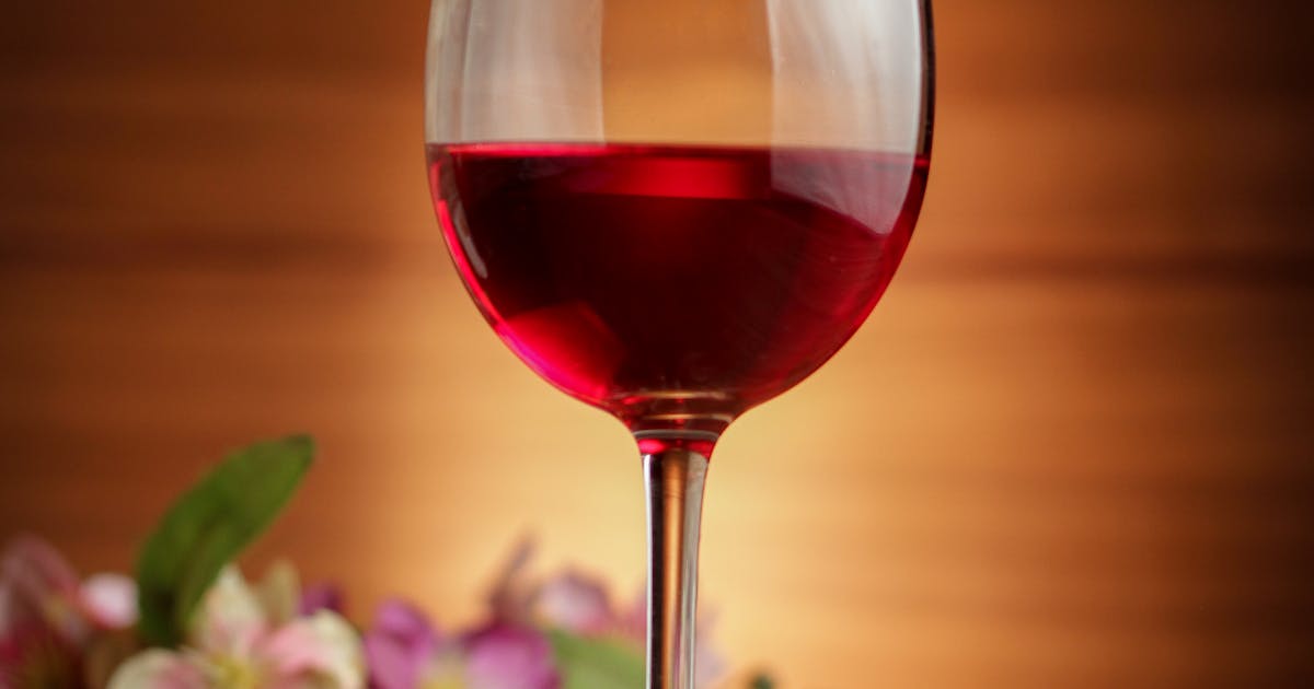Glass of red wine on a wooden table at dusk representing alcohol and gut health