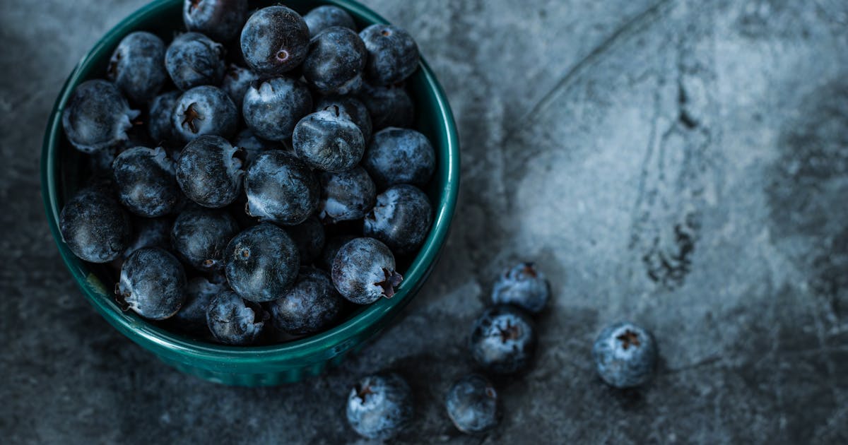 Fresh blueberries in a small bowl in moody natural light for mitochondrial health