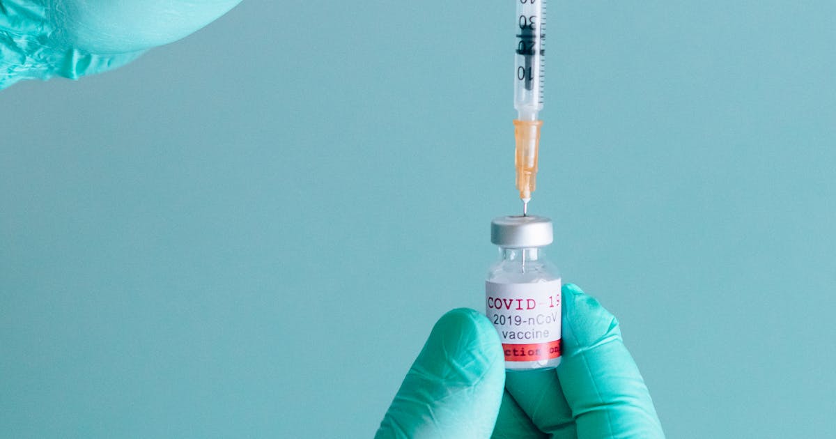A Person Holding a Syringe and a Vial