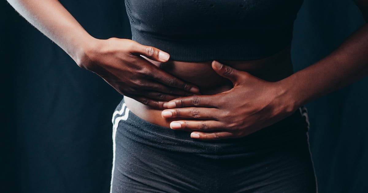 Close-up of a person pressing hands on abdomen indicating discomfort or pain