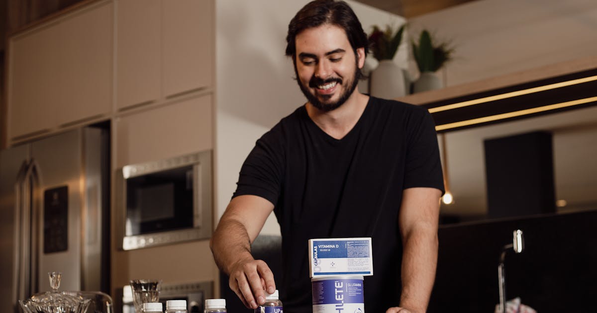 Smiling man arranging vitamin supplements on kitchen counter