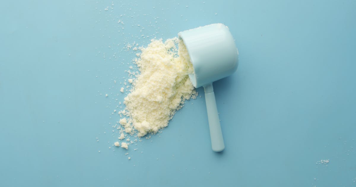 White powder and a scoop on a blue background representing creatine supplement
