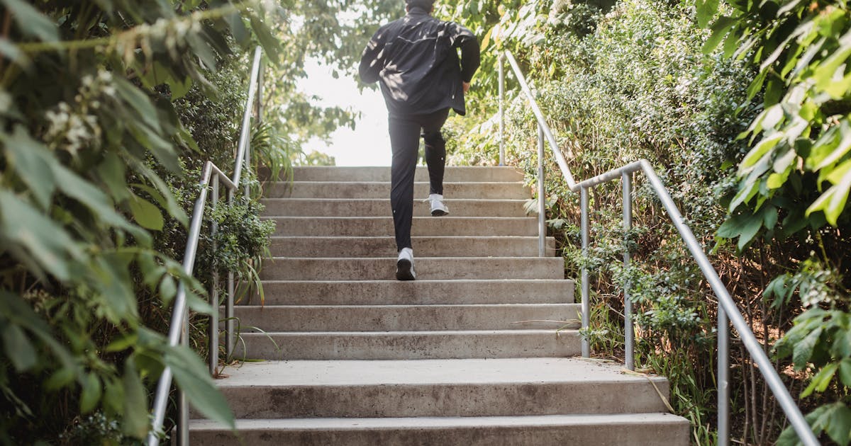 Adult runner sprinting up outdoor stairs in athletic gear