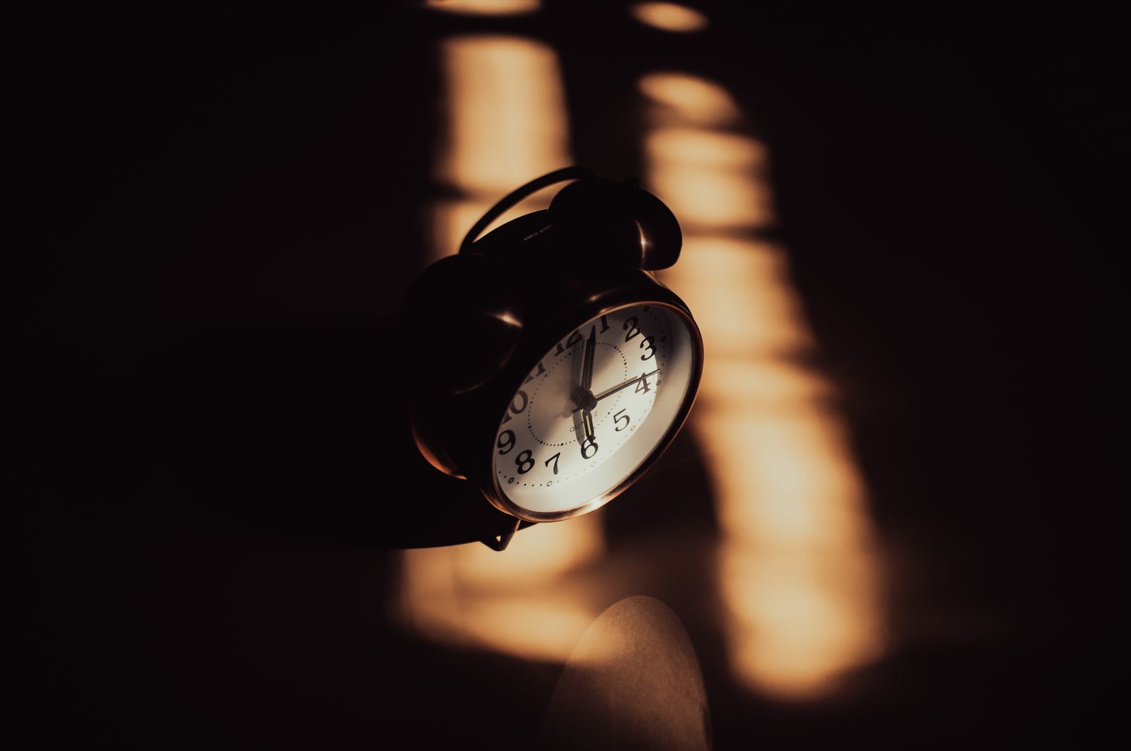 A bedside alarm clock glowing in a dark bedroom just past 3am