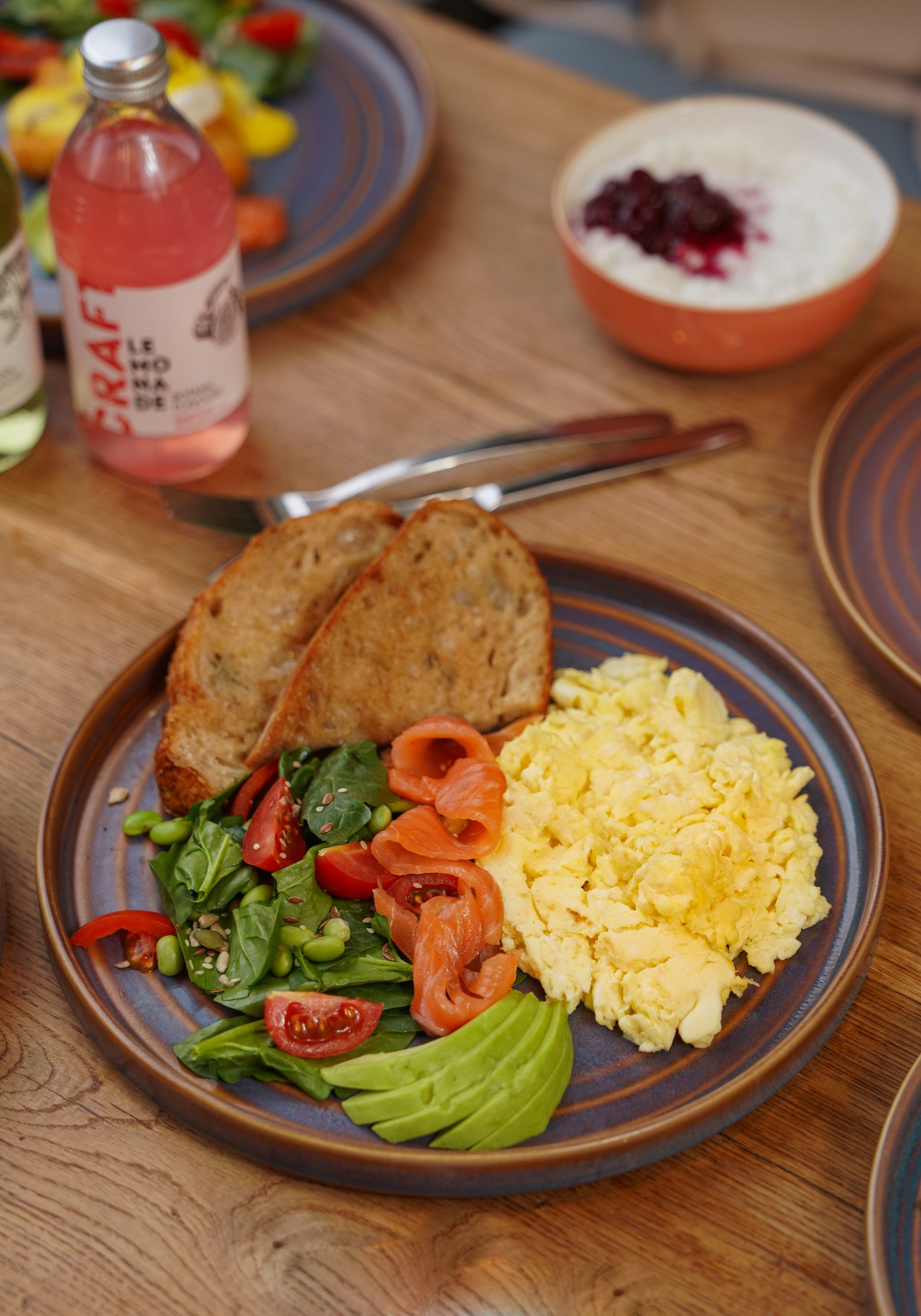 A breakfast plate of scrambled eggs, smoked salmon, greens and wholegrain toast