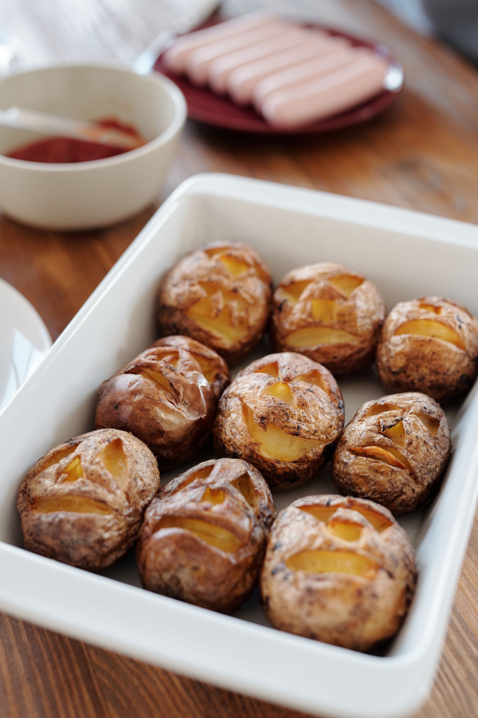 Whole potatoes baked in their skins and split open in a white ceramic dish