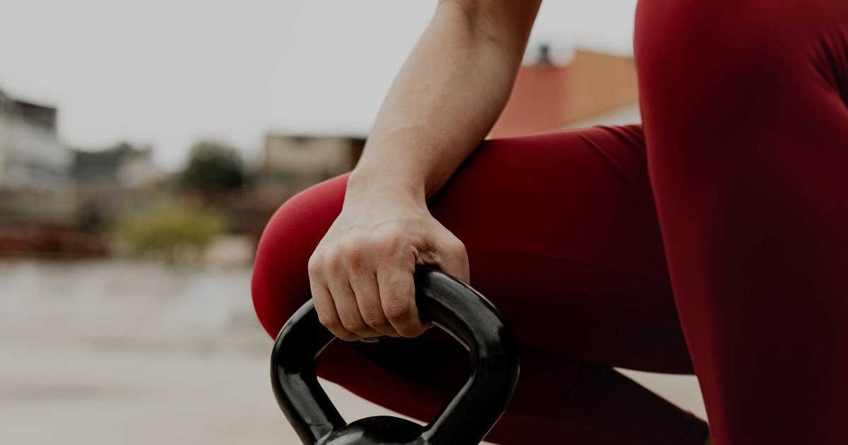 A woman in athletic wear training with a kettlebell outdoors