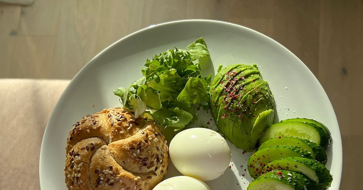 A plate of no-cook high-protein foods including boiled eggs, smoked salmon, cheese, and avocado