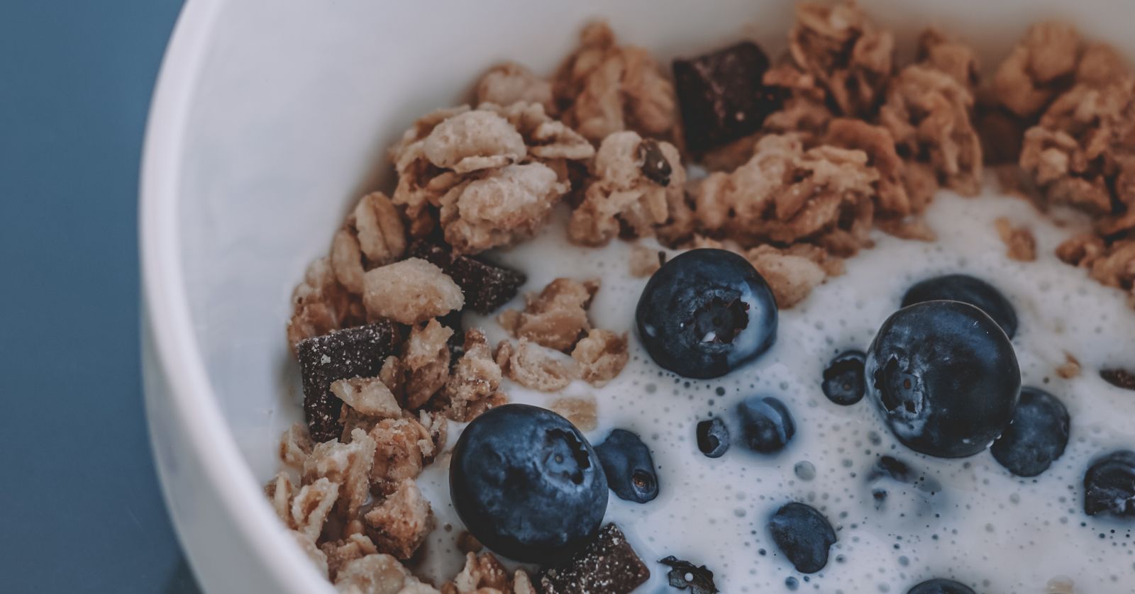 A bowl of whole-grain cereal with blueberries and milk