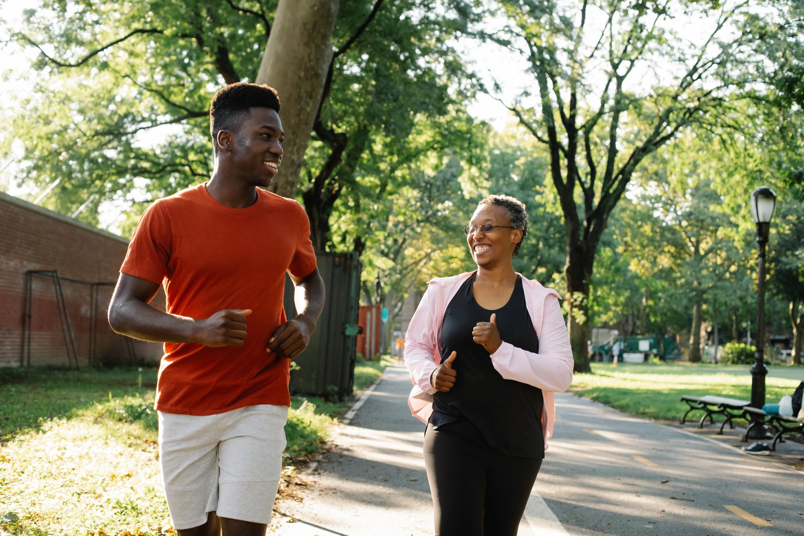 Two people jogging together in a sunny park, one older and one younger