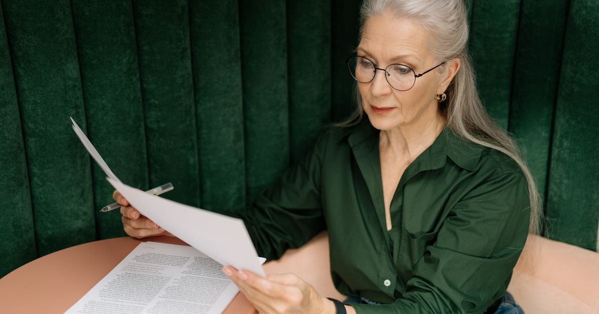 An older woman in reading glasses concentrating on a document she is holding