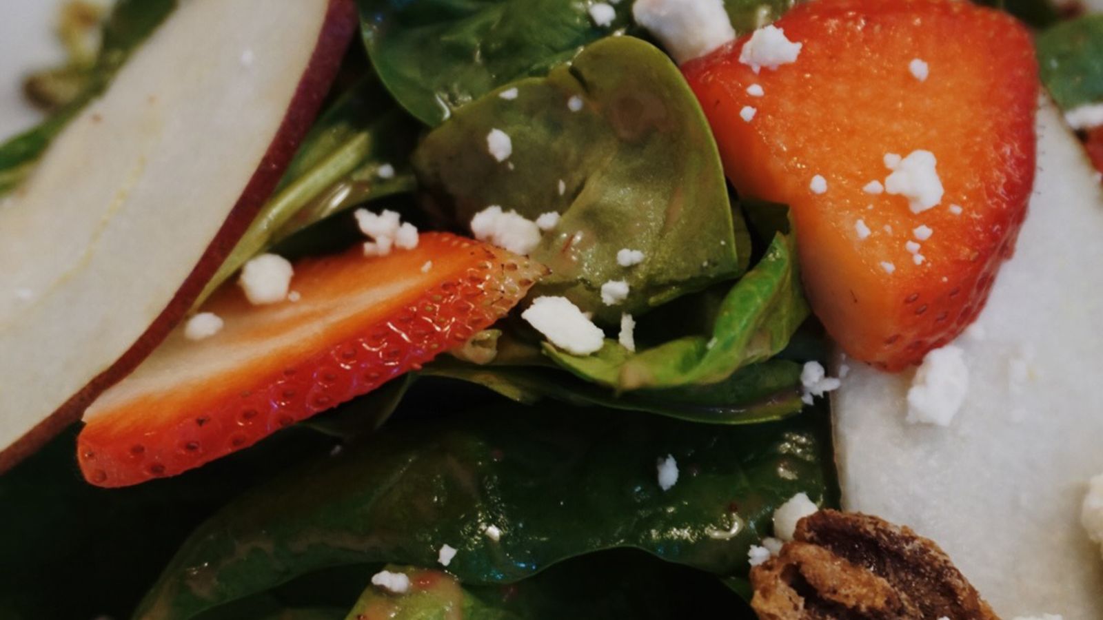 A fresh spinach salad with strawberries and cheese