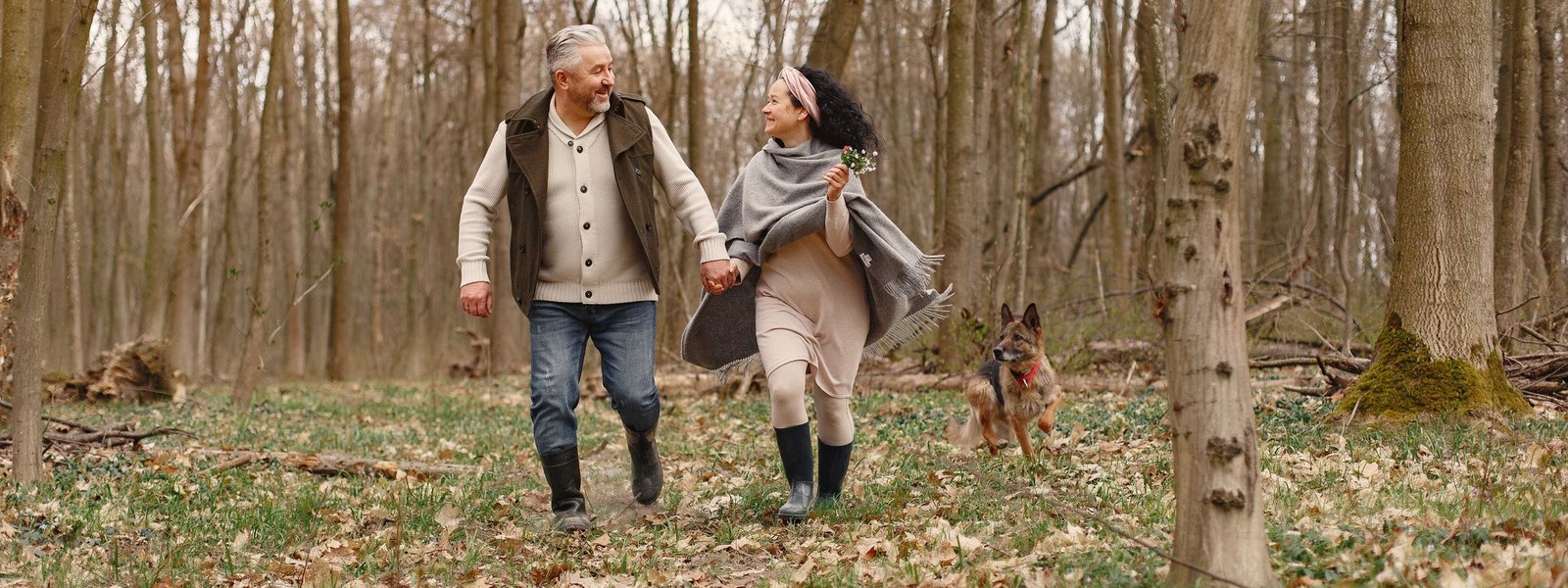 A couple walking together along a wooded path on a cool morning