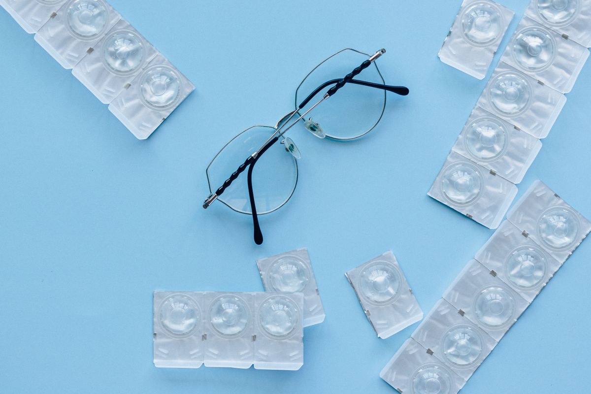 A pair of eyeglasses on a blue surface surrounded by lens cases
