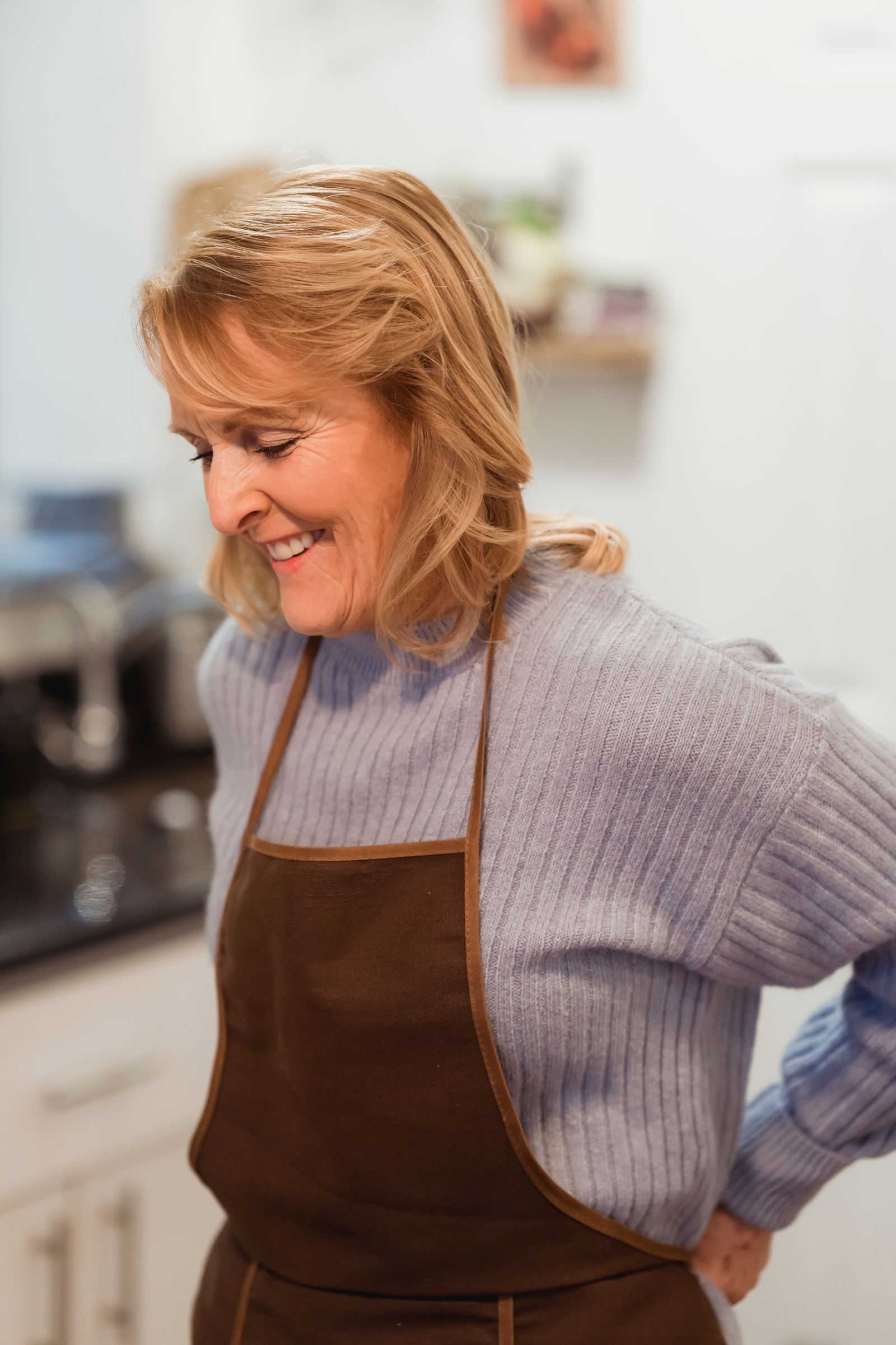 A woman in her fifties smiling in her kitchen