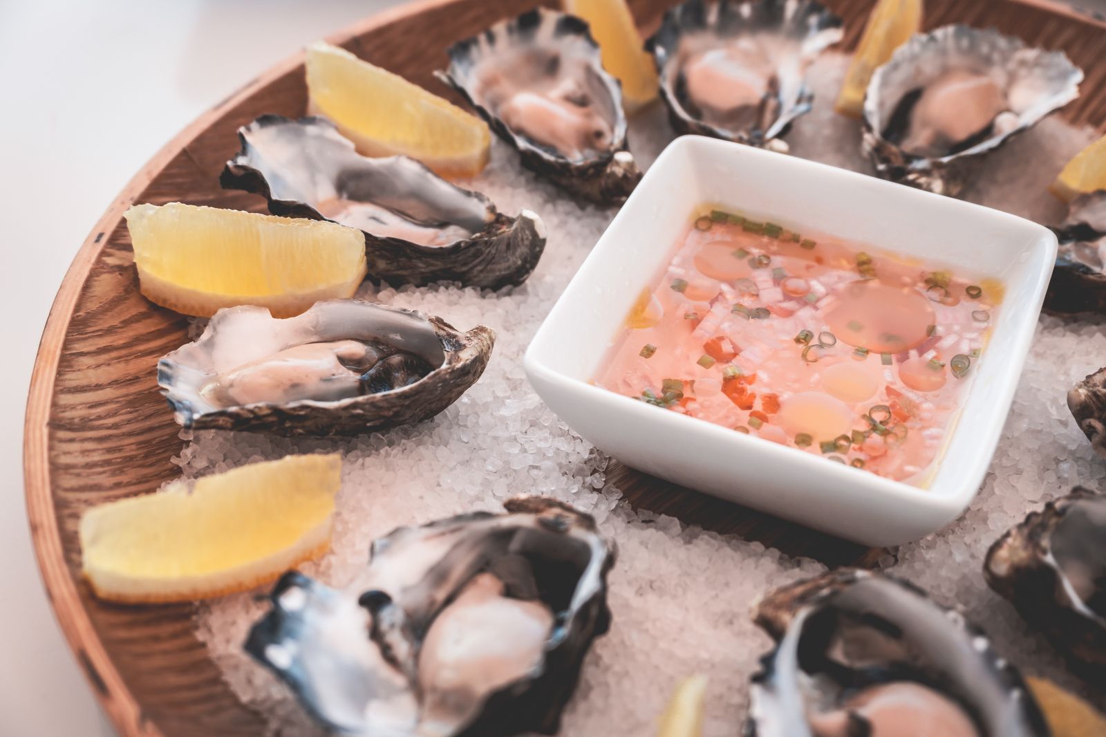 Fresh oysters on ice with lemon wedges on a wooden serving board