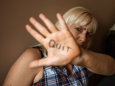 A woman holds up her palm with the word Quit written on it