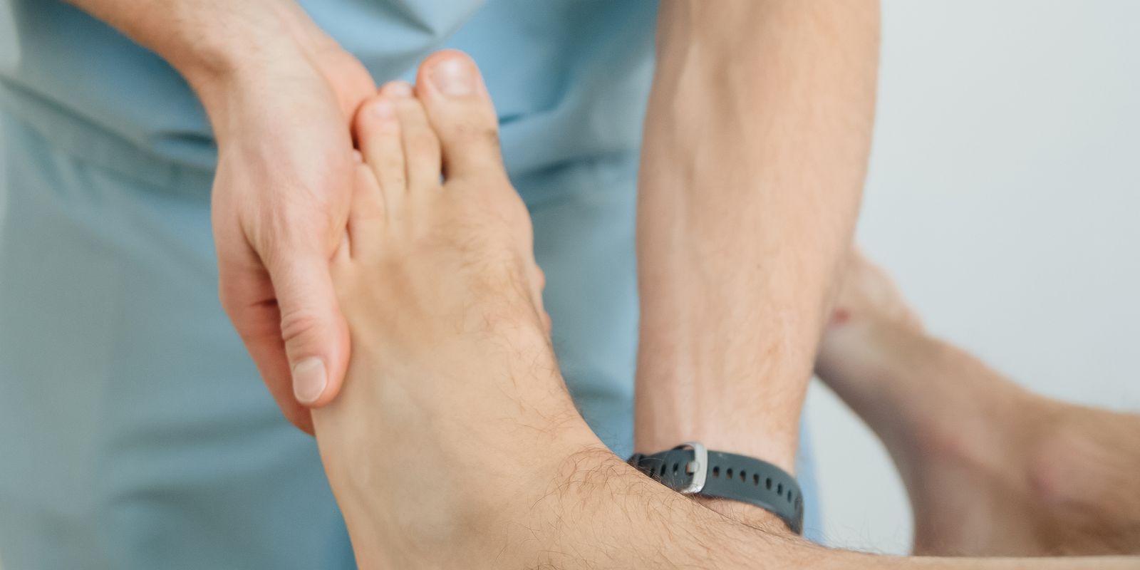 A clinician examining a patient's bare foot and big toe
