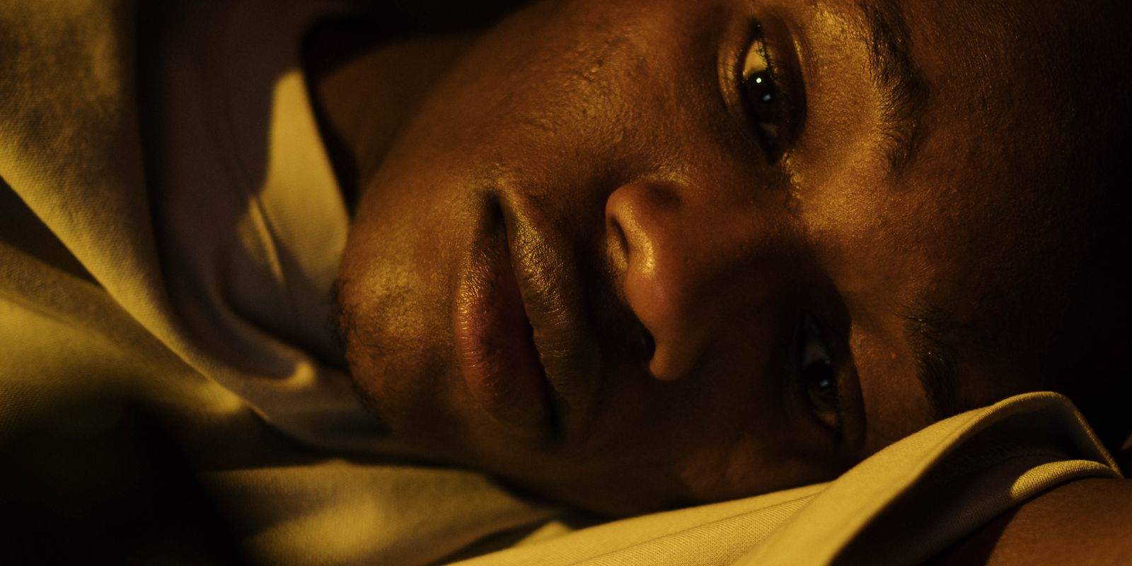 A man lying awake in bed at night with his eyes open