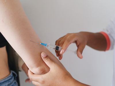 A clinician giving a vaccination injection into a patient's upper arm
