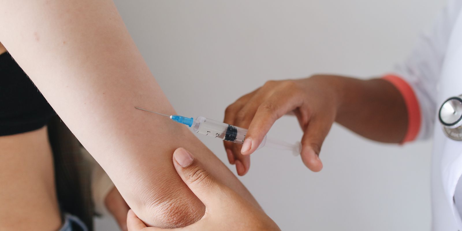 A clinician giving a vaccination injection into a patient's upper arm