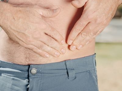 A person pressing both hands against the upper abdomen
