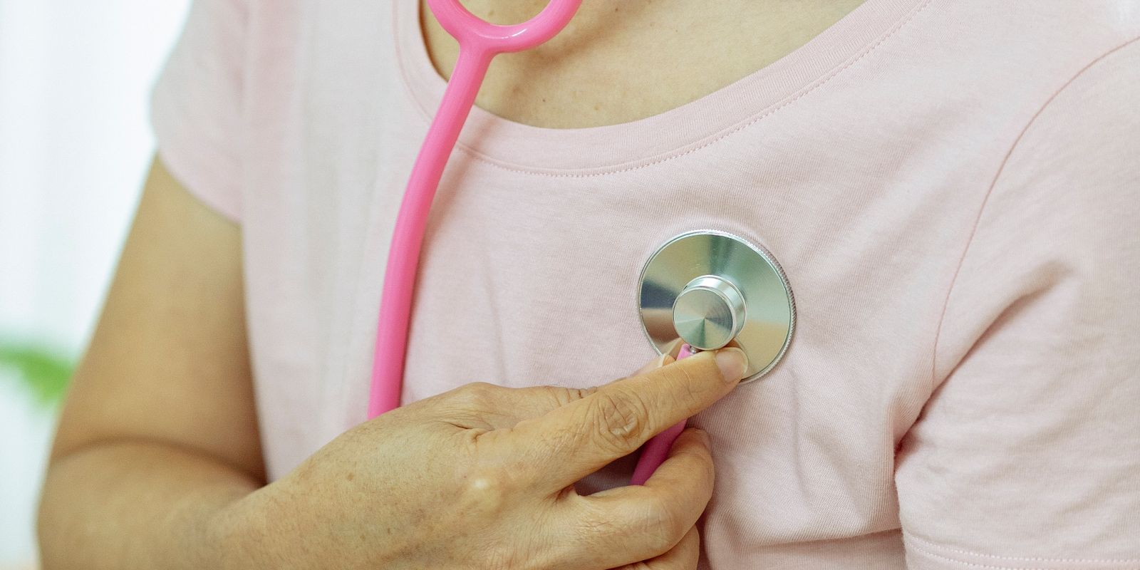 A hand holding a stethoscope against a person's chest