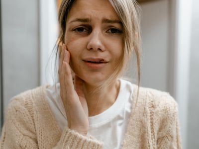 A woman holding the side of her jaw with a pained expression