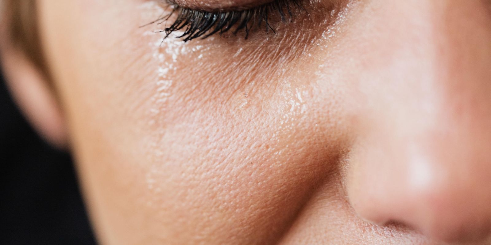 A close-up of a woman's face with a tear running from her eye