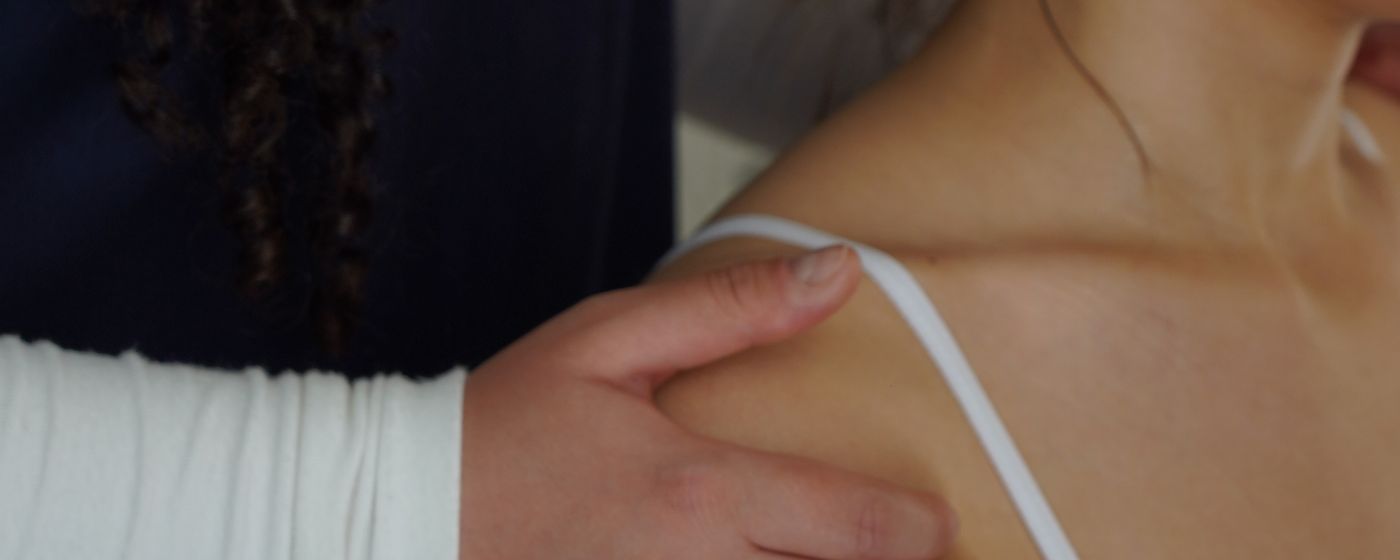 A therapist's hands supporting a patient's shoulder during a session