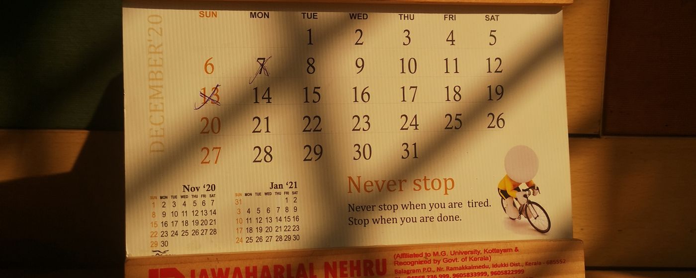 A paper wall calendar hanging in warm window light