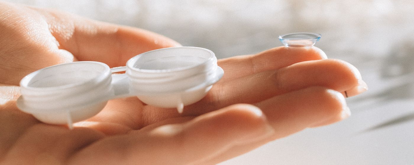 A pair of open contact lens cases held in an upturned palm