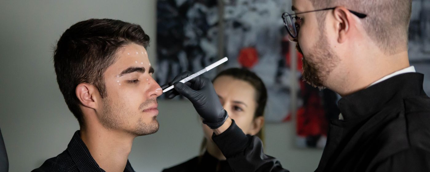 A surgeon marking measurements on a patient's face during a clinic consultation