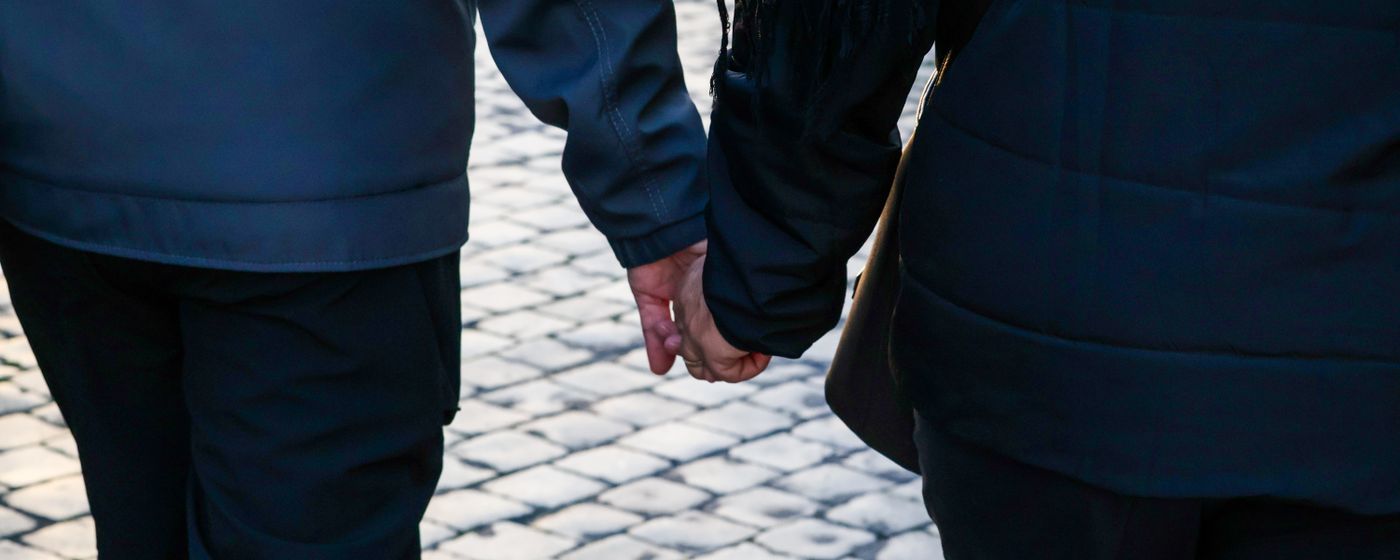 Two people walking side by side and holding hands along a cobbled street