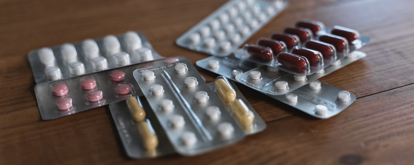 Several blister packs of tablets and capsules laid out on a wooden table