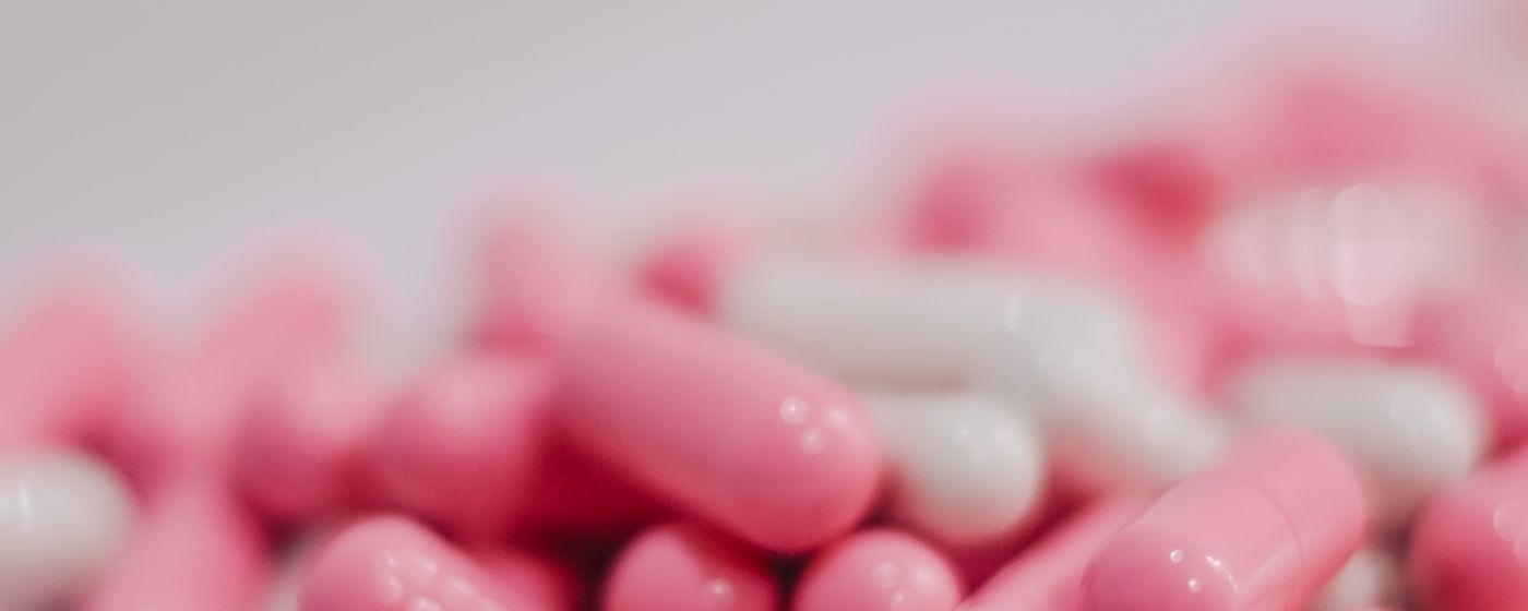 Pink and white medicine capsules in soft focus