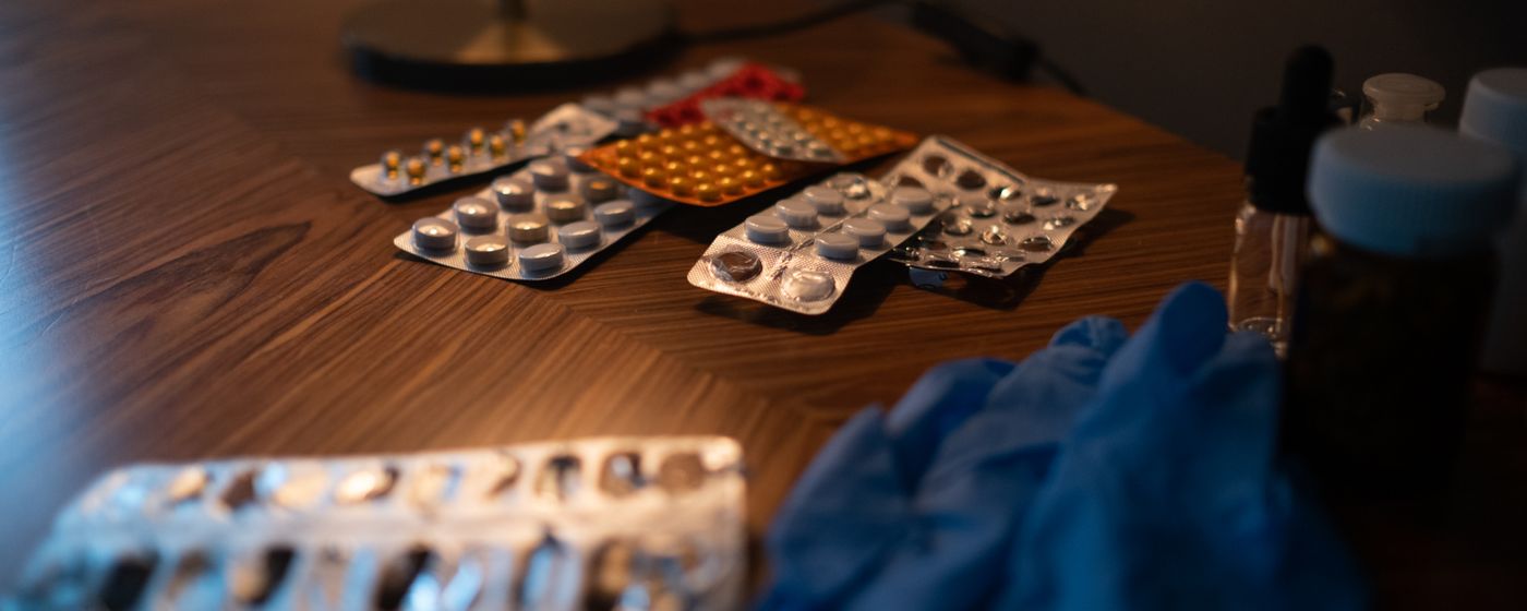 Several blister packs of tablets and capsules lying on a dark wooden table
